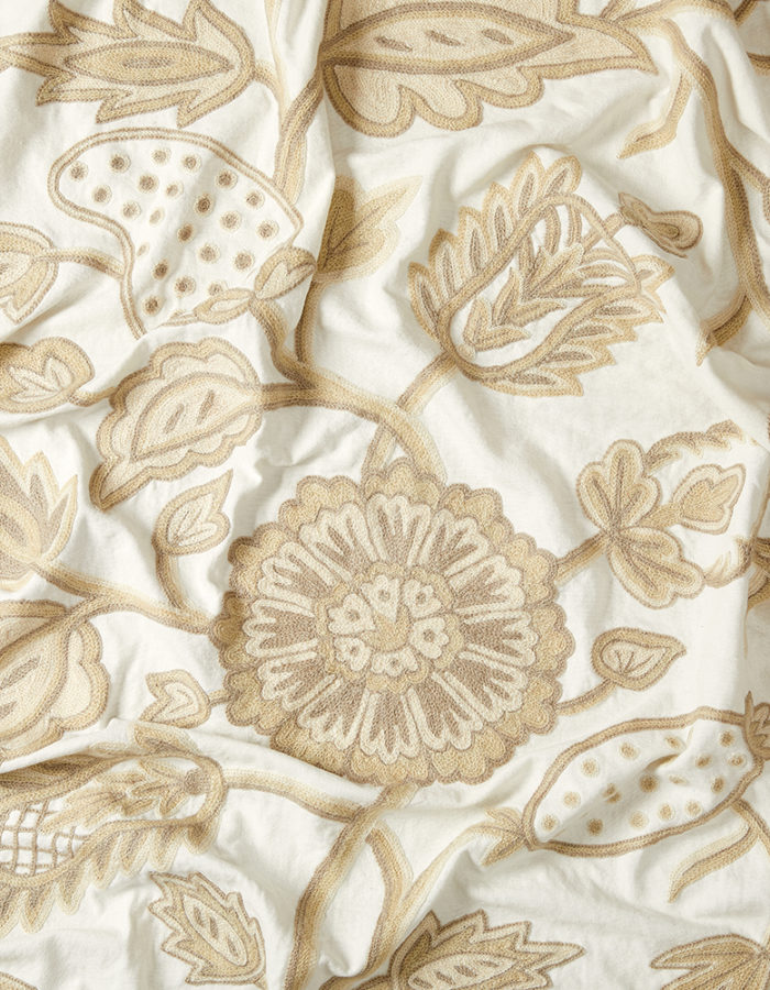 Crewel fabric. Cream cotton background with trailing floral embroidery in shades of taupe and cafe au lait.